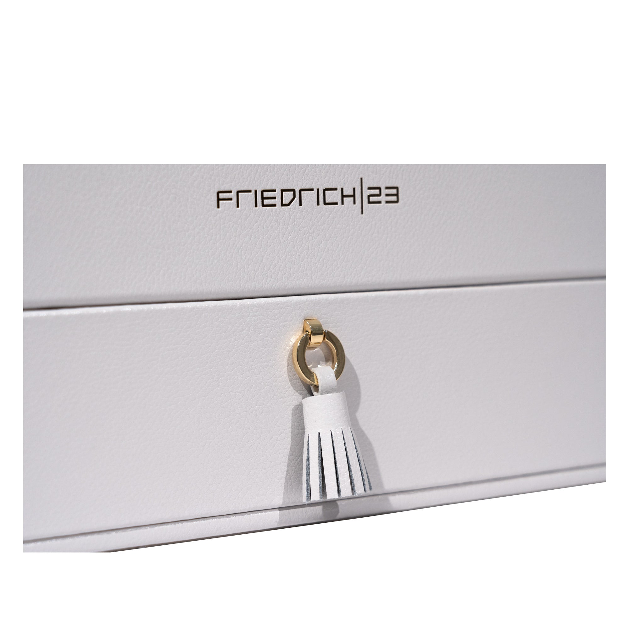 Detailaufnahme hellgrauer Schmuckkoffer aus Leder mit Friedrich23 Logo in Goldprägung sowie Lade mit Zierquaste und Detail in Goldoptik.