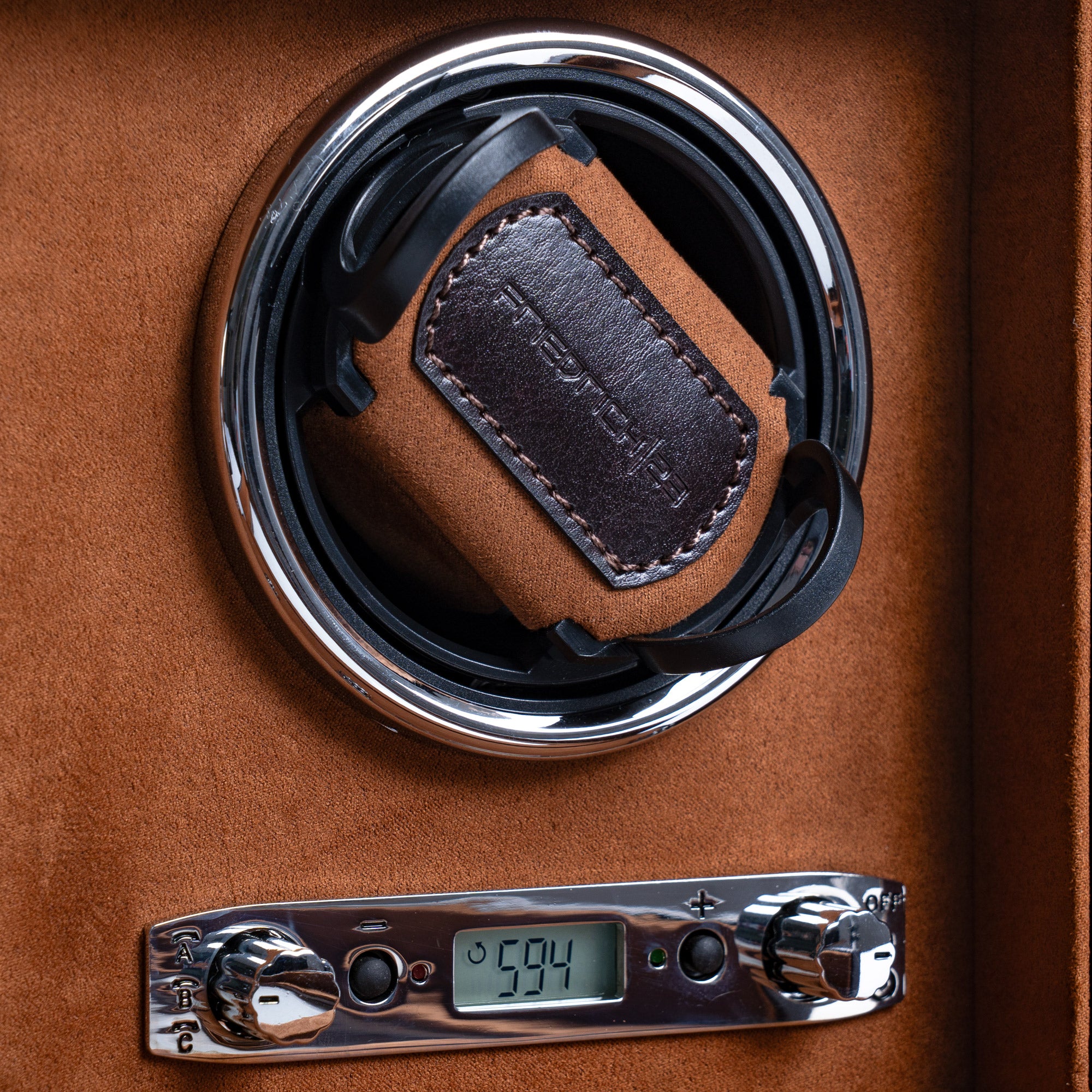 Detailansicht eines Uhrenbewegers aus braunem Leder mit hellbraunem Velourstoff, Drehknopfleiste mit LCD-Anzeige