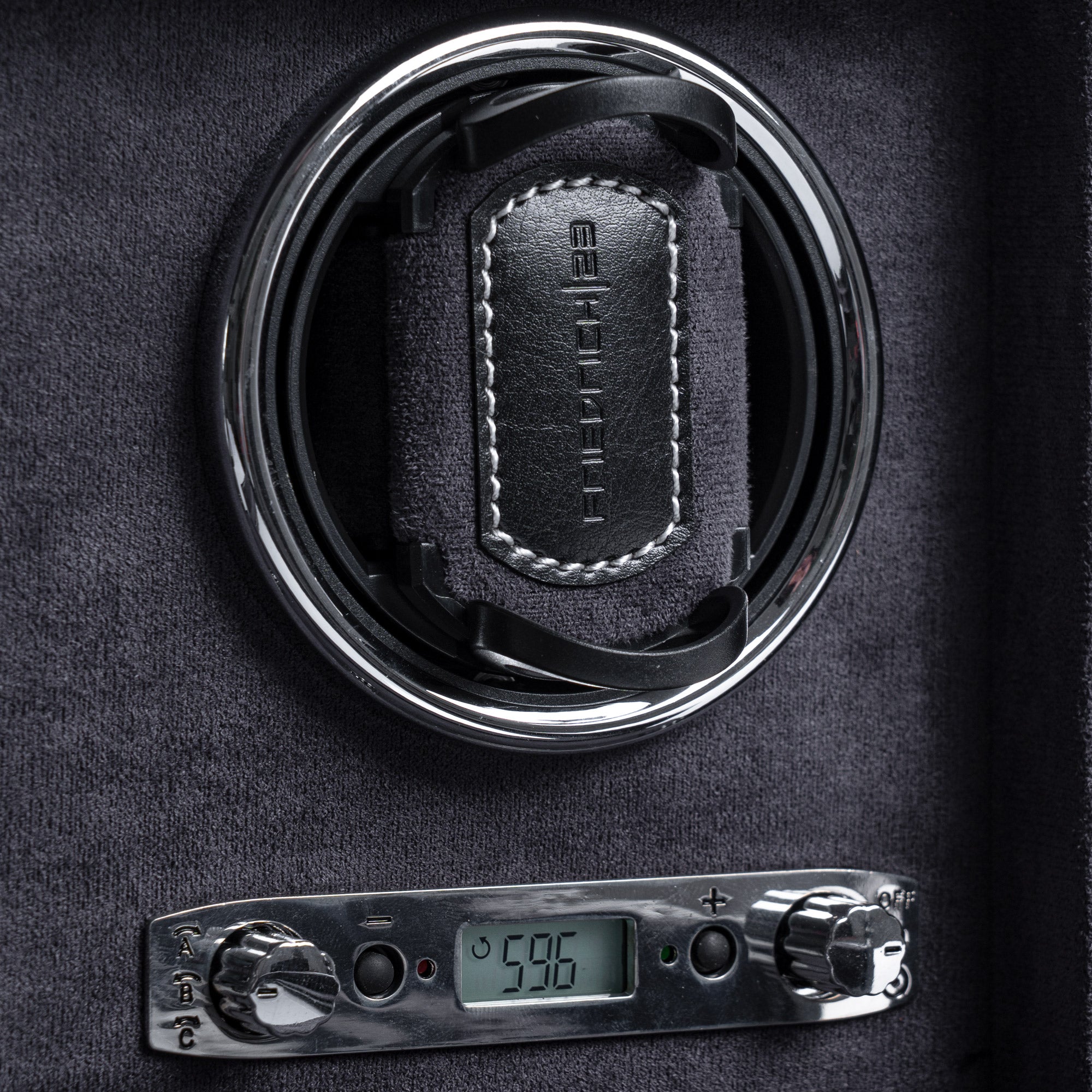 Detailansicht eines Uhrenbewegers aus schwarzem Leder mit grauem Velourstoff, Drehknopfleiste mit LCD-Anzeige