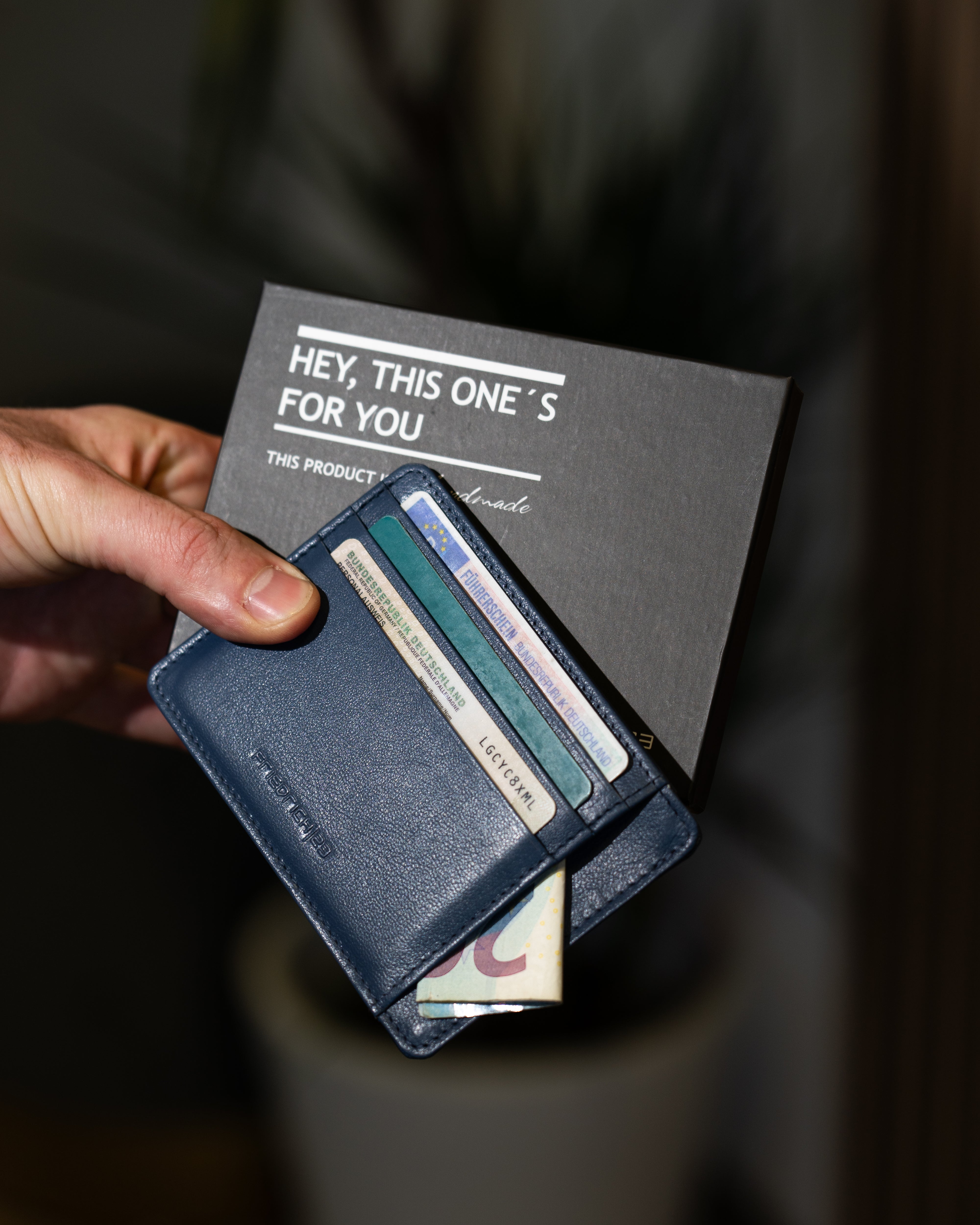 Blaugraues Kartenetui aus Leder in Hand gehalten