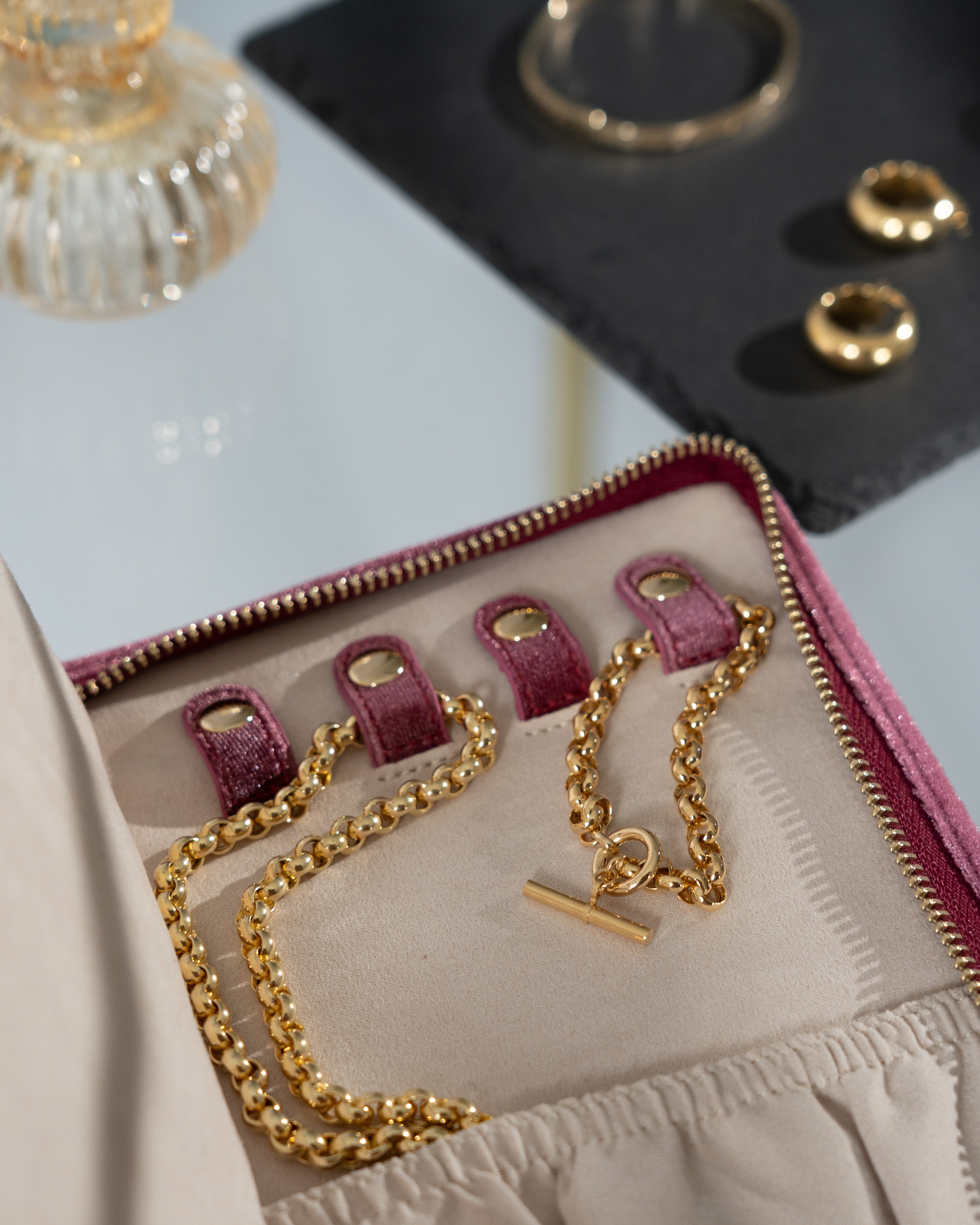 Detailansicht Schmucketui aus Samt in Fuchsia auf Glastisch mit Schmuck befüllt.