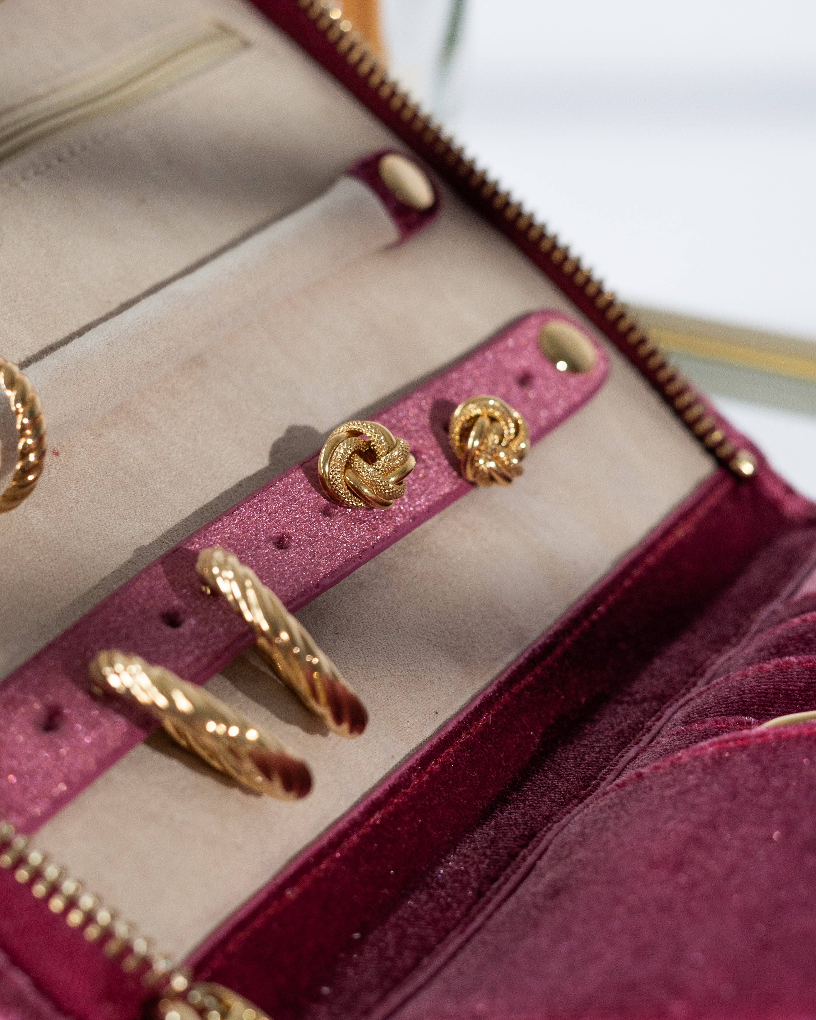 Detailansicht Schmucketui aus Samt in Fuchsia auf Glastisch mit Schmuck befüllt.