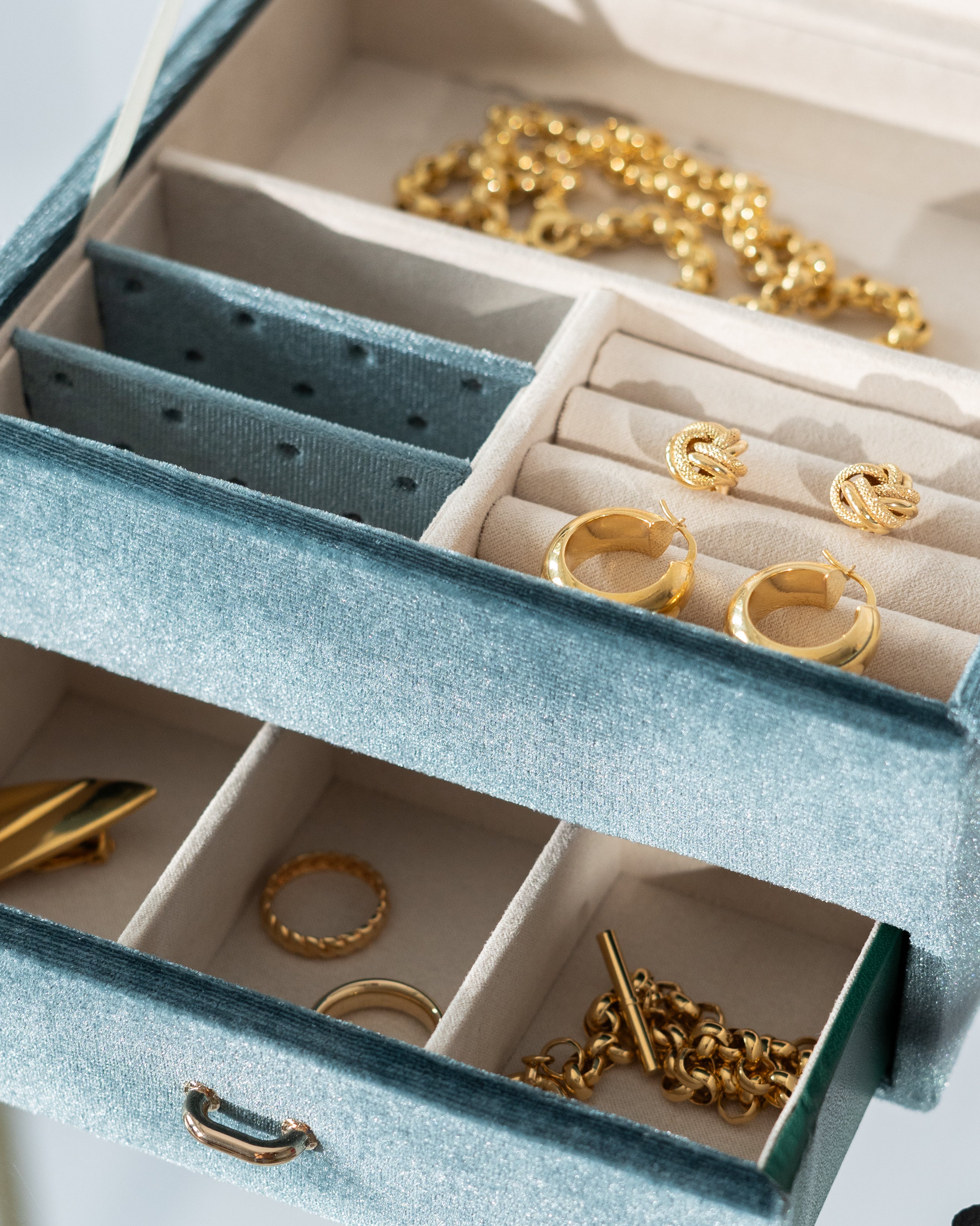 Detailaufnahme türkises Schmuckkästchen aus Samt mit Schmuck befüllt.