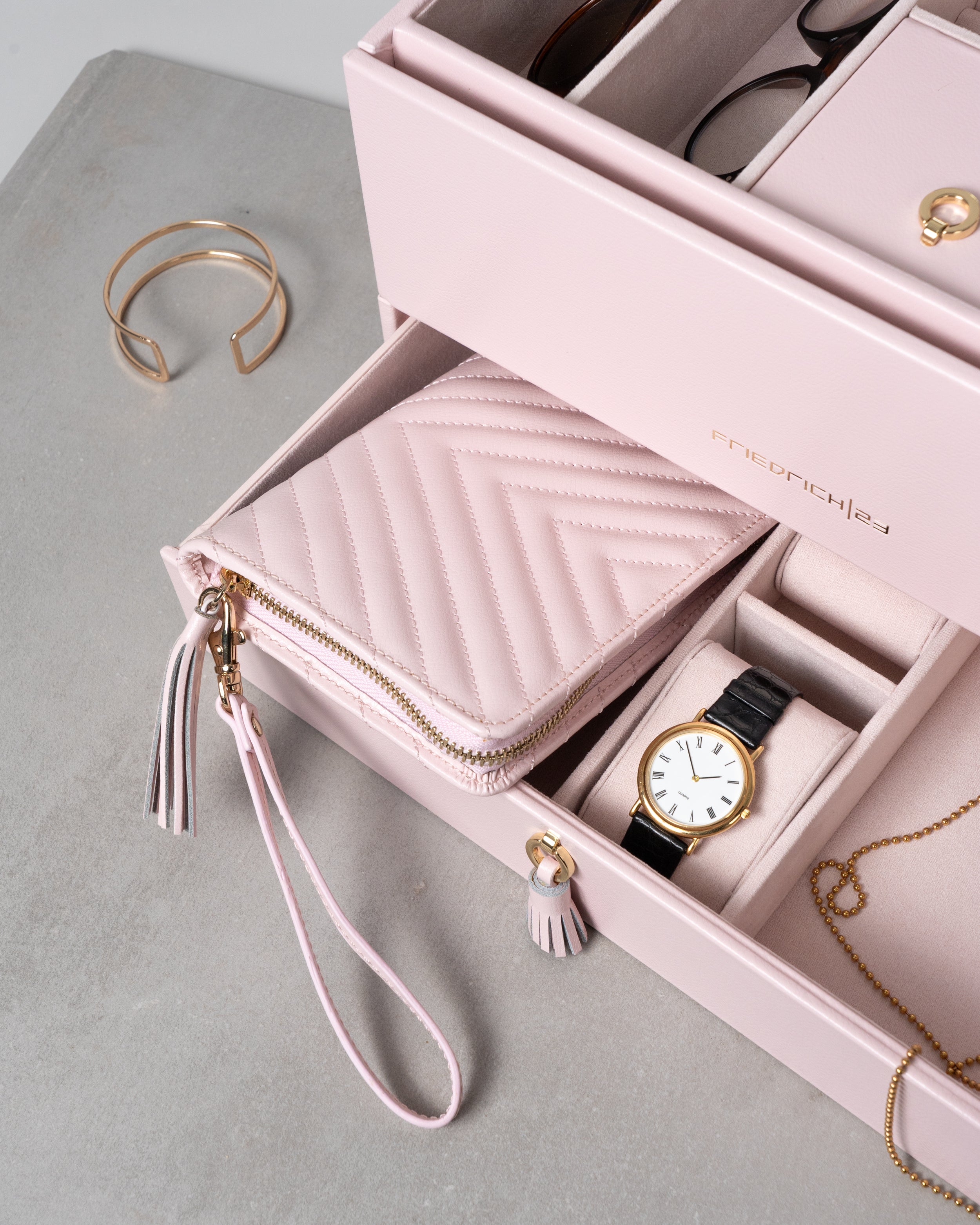 Geöffneter rosa Leder Schmuckkoffer mit Schmuck, Uhren und Brillen.
