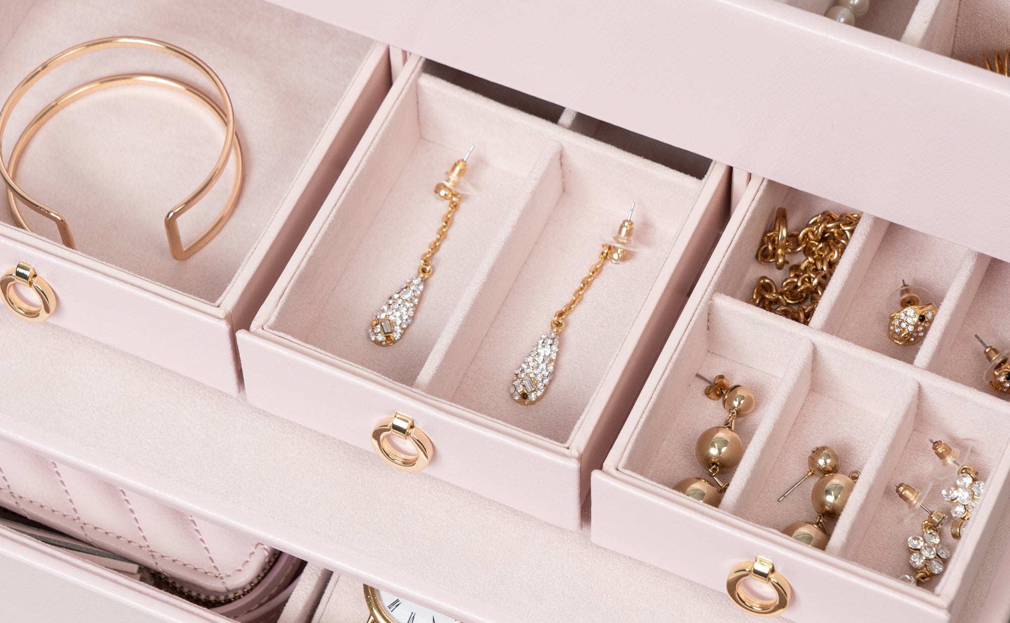 Viele kleine Fächer, darin liegen Ohrringe und Armreifen, sowie Ohrstecker