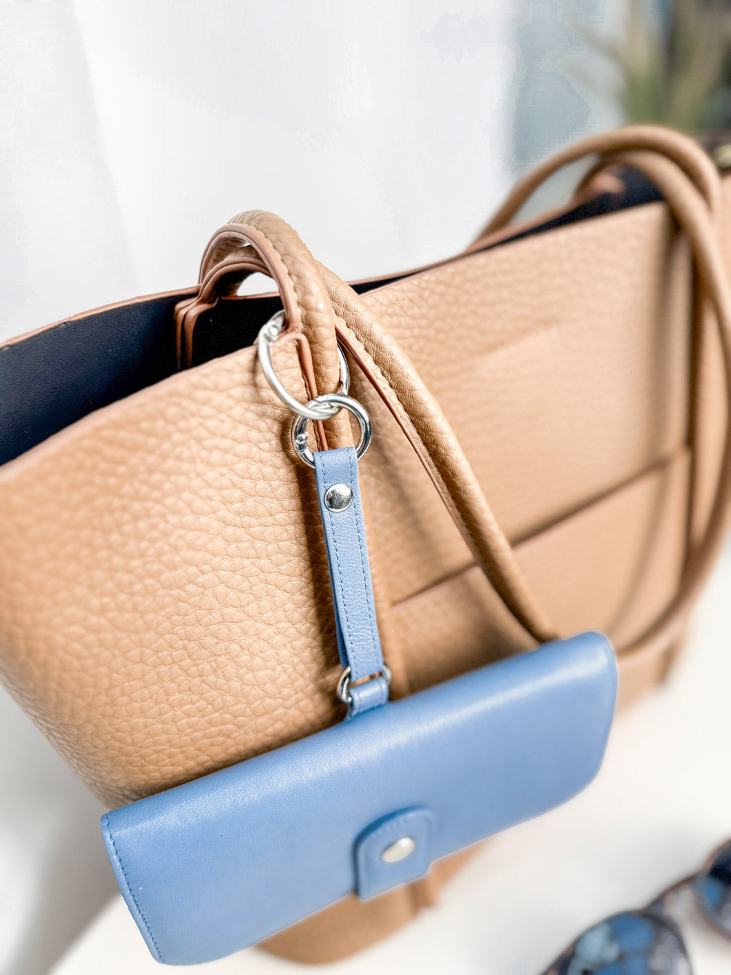 Detailansicht von einem Karabiner an dem das Brillentui an einer Handtasche befestigt ist.