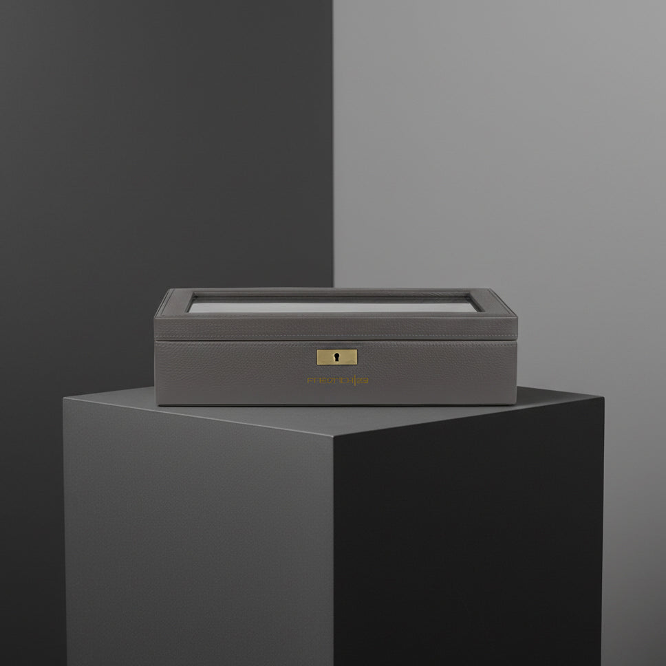 Grauer Uhrenkasten mit Glasdeckel auf eine Bodest