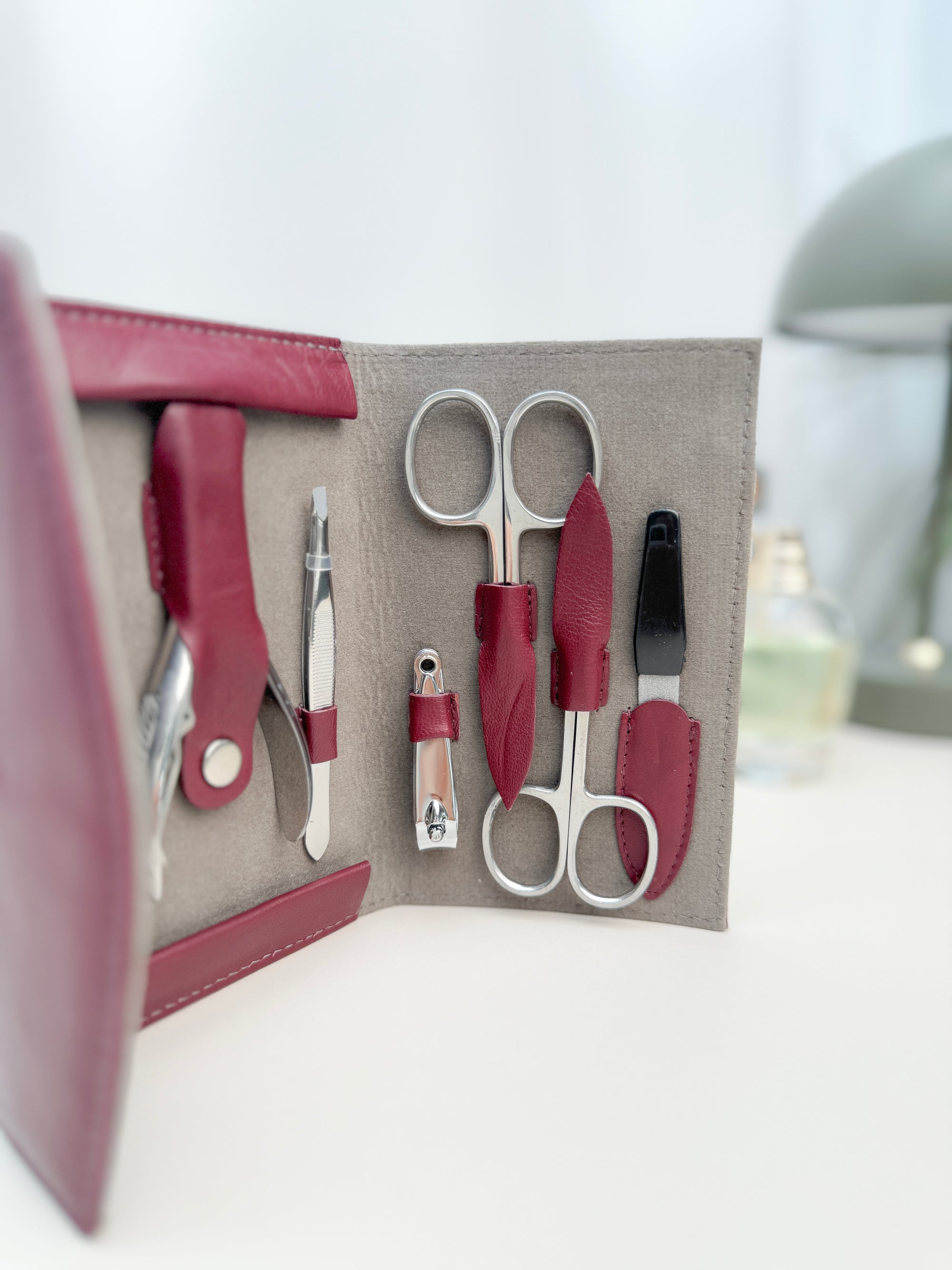 Großaufnahme von einem Lederetui welches geöffnet auf einem Tisch steht und man sieht das Manikür-Besteck.